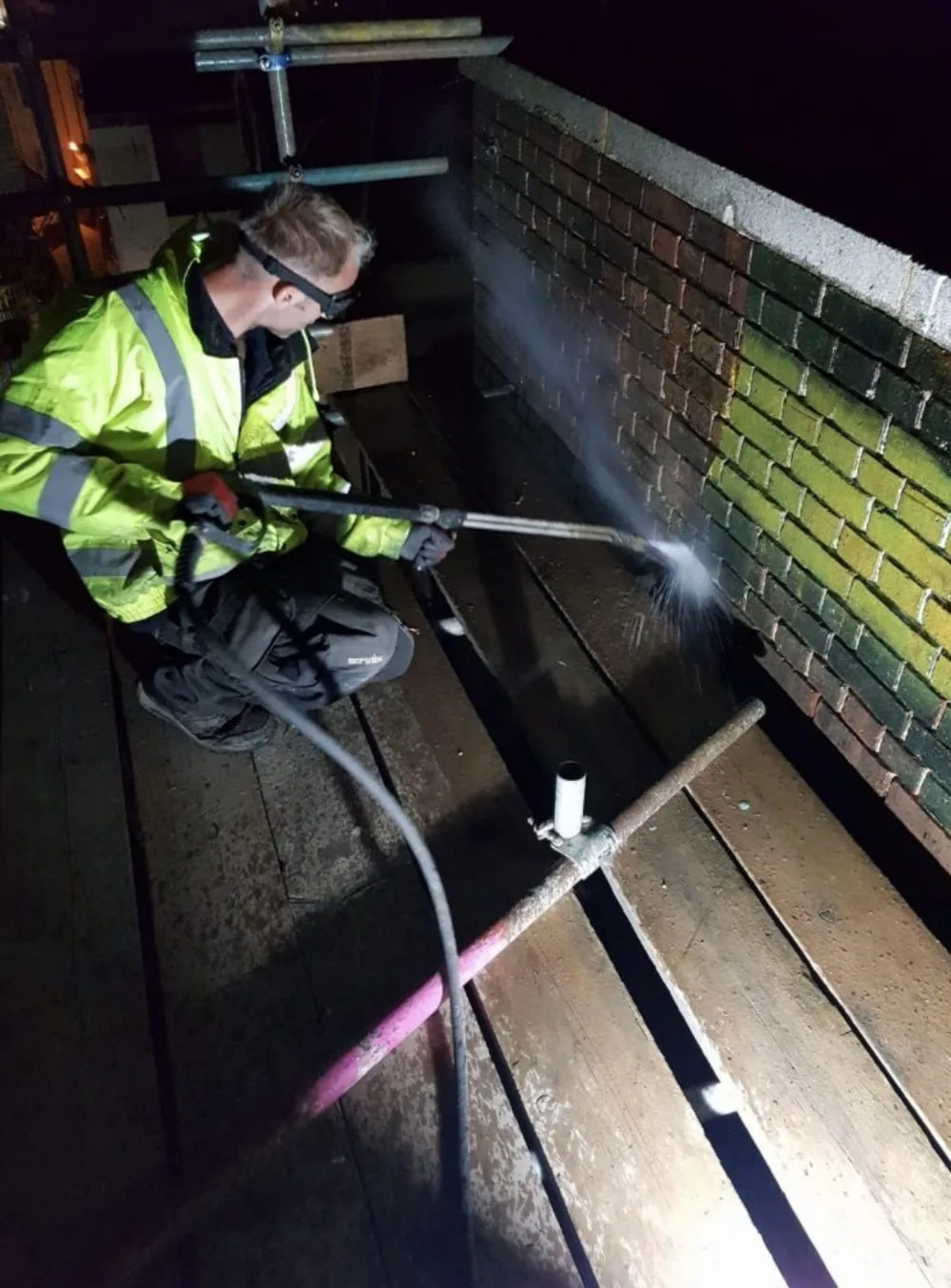 Removing graffiti and green staining from a brick wall on a night commercial job in East Kent
