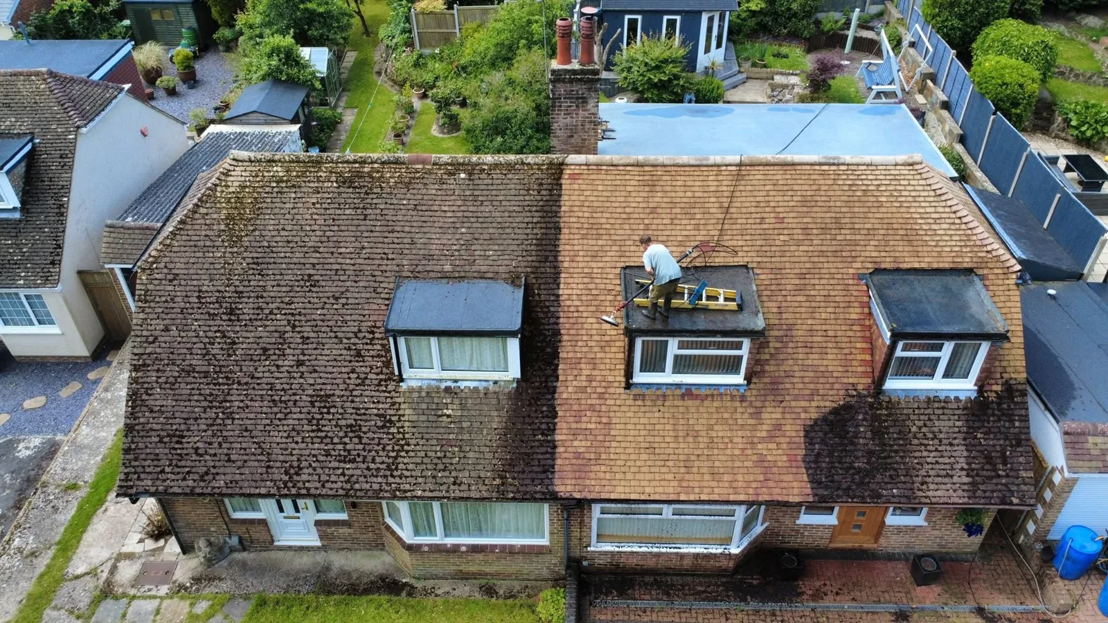 Roof cleaning in progress in Kent showing dirty moss-covered tiles on the left and clean tiles on the right after soft washing