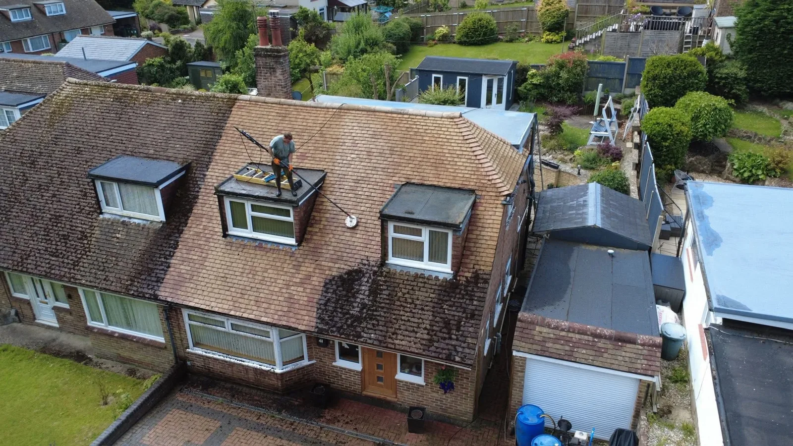 Sharps Exterior Cleaning soft washing a tiled roof from a roof ladder in Kent